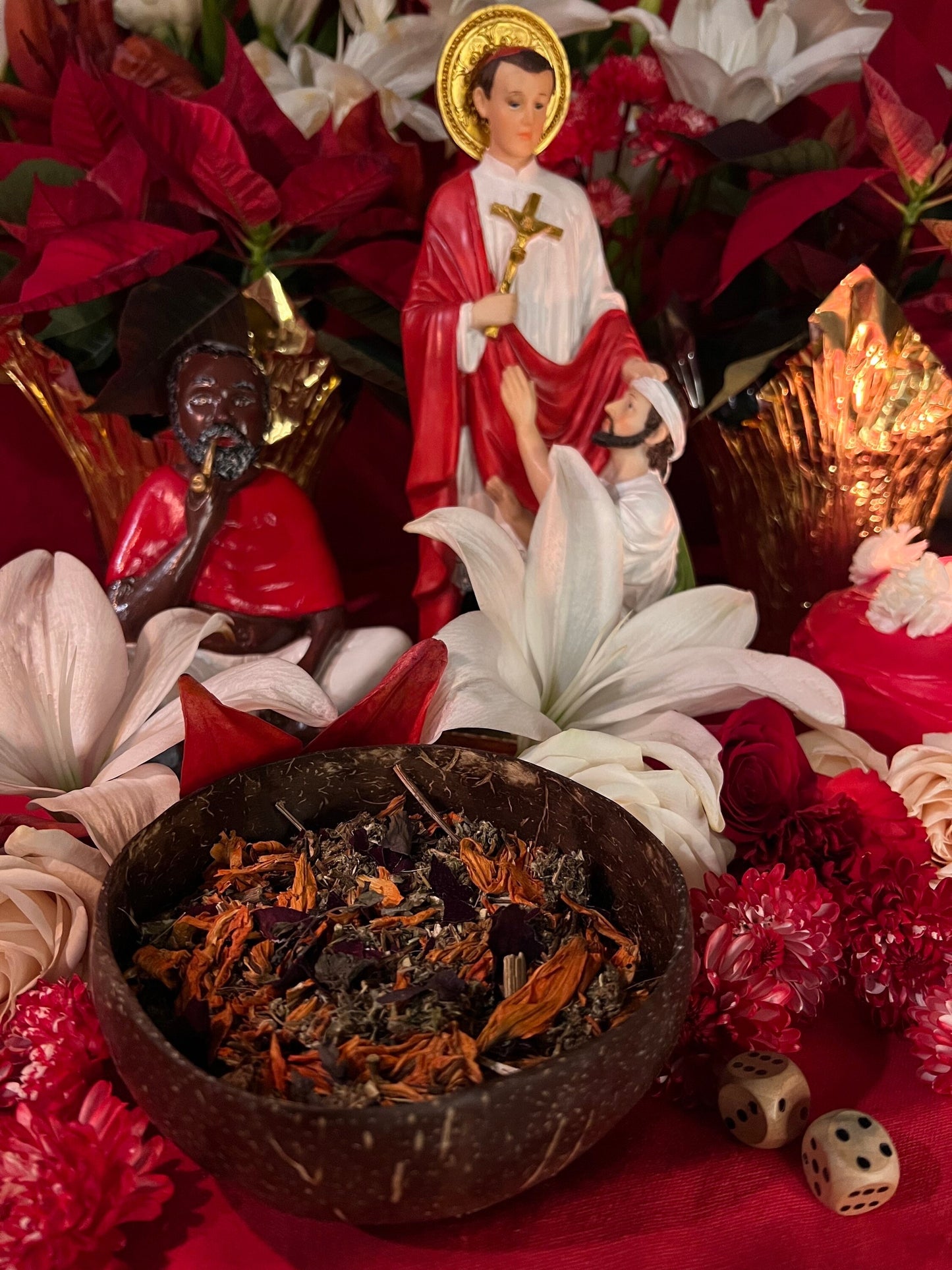 May include: A brown coconut bowl filled with dried herbs and flowers. The bowl is sitting on a red surface with a white flower, red flowers, and two dice.